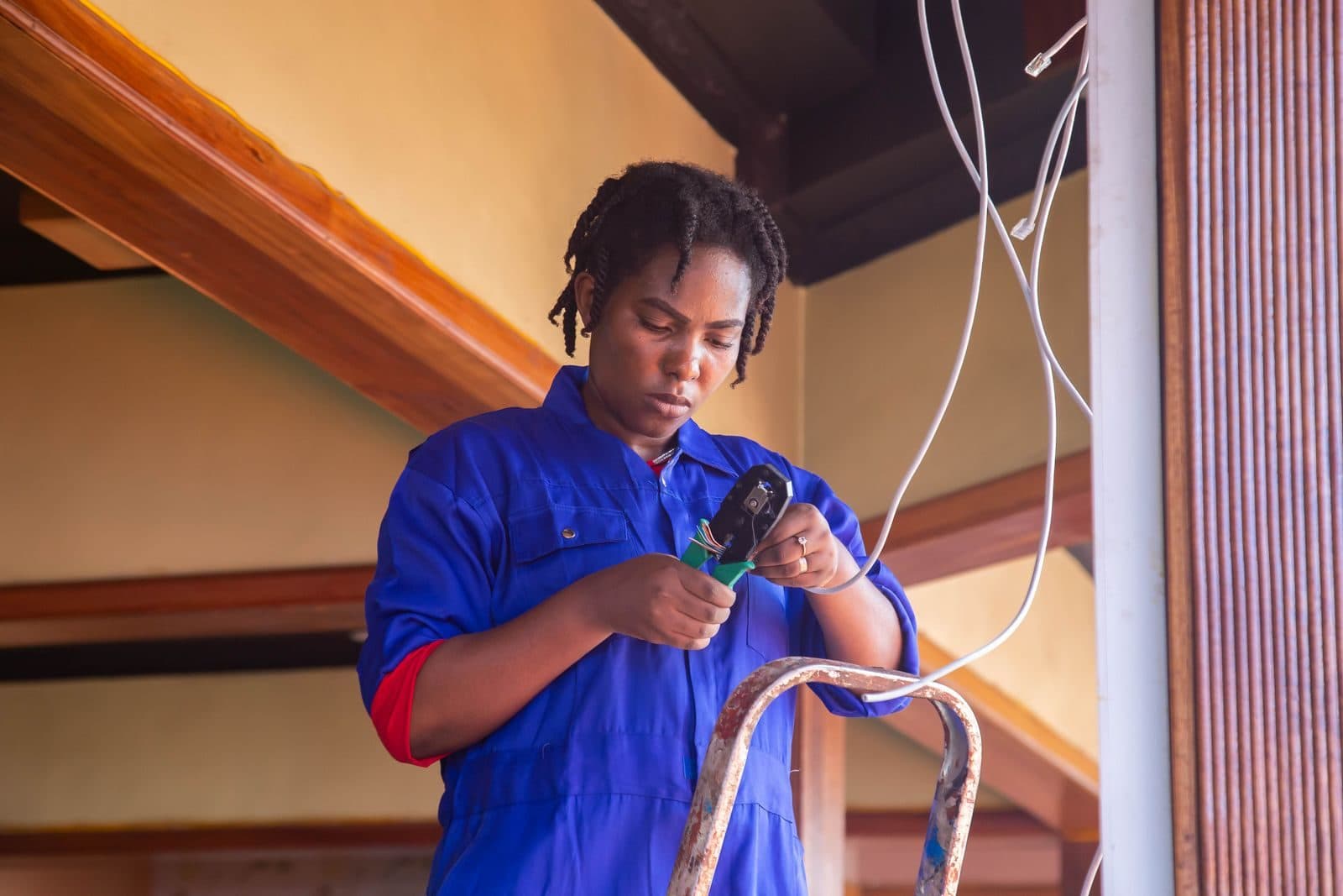 Electrician in blue coveralls working on ceiling wiring