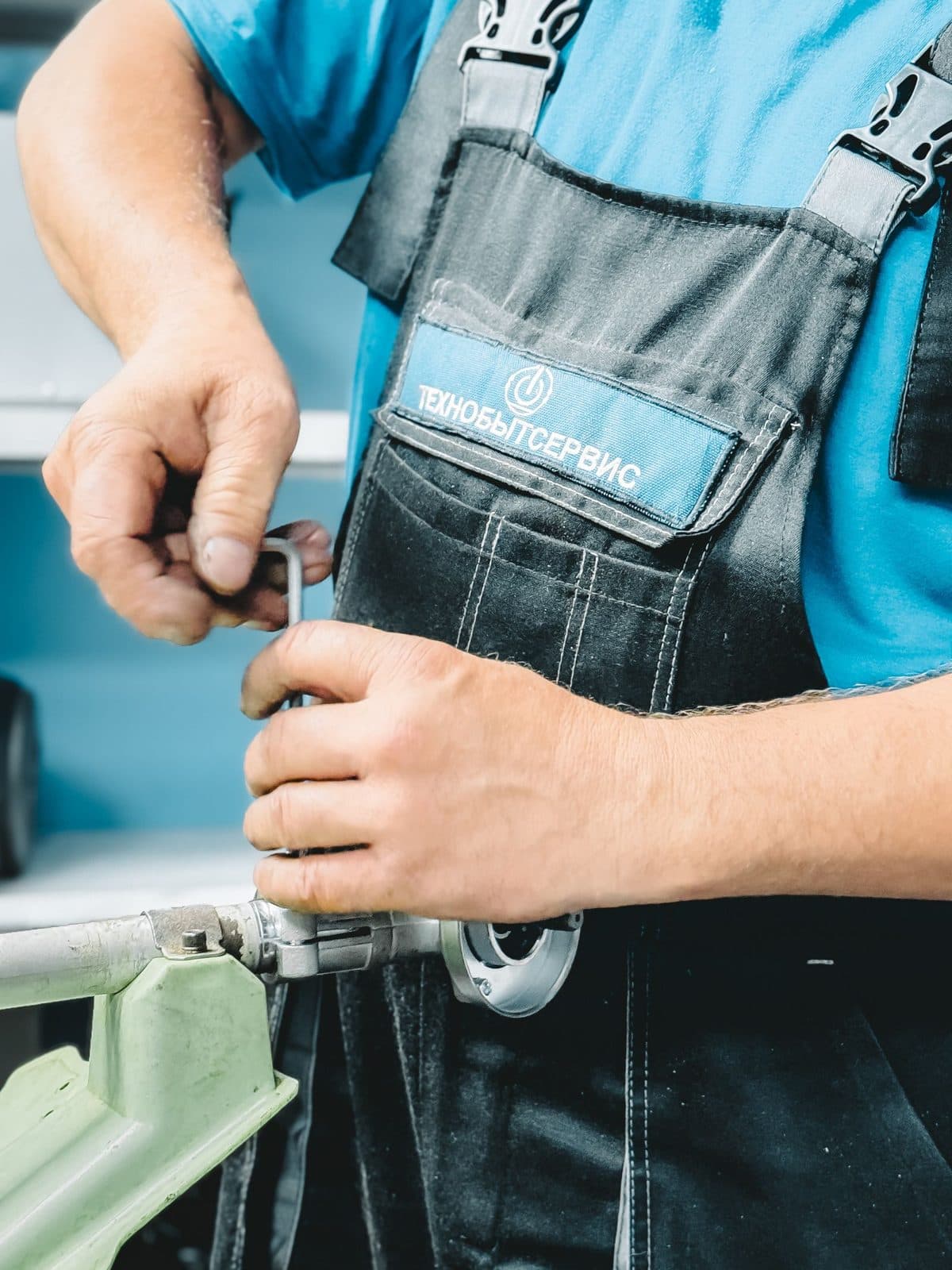 Plumber in a blue uniform tightening a pipe fitting with a wrench